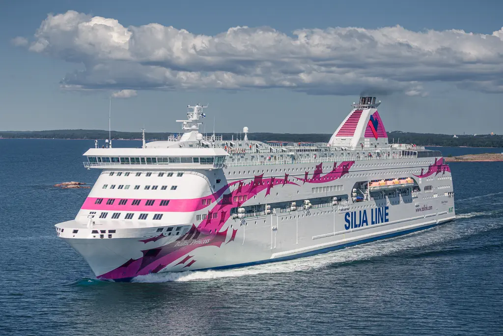 Fährschiff mit buntem Design auf offenem Wasser mit einigen Wolken am Himmel. Das Schiff hat die Aufschrift „SILJA LINE“.