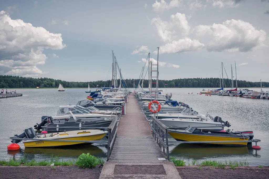 Hafen in Loviisa mit mehreren Booten an einem Holzsteg, umgeben von ruhigem Wasser und bewölktem Himmel.