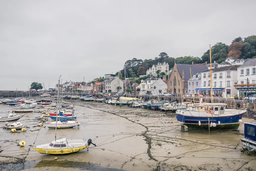 Hafen mit mehreren Booten im Trockenen, umgeben von niedrigen Gebäuden und Bäumen auf einer bewölkten Tageslichtszene.