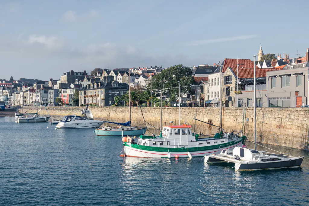 A scenic harbor with an array of boats, colorful buildings lining the shore, and calm waters reflecting the clear sky.