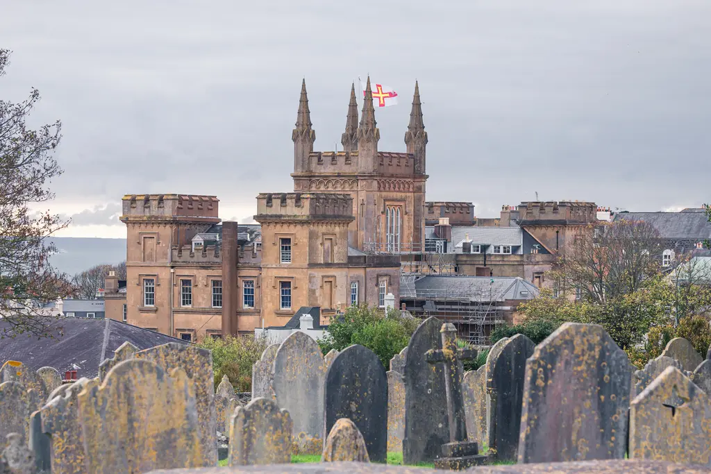 A stone castle with spires stands in the background, framed by an old cemetery with weathered gravestones.
