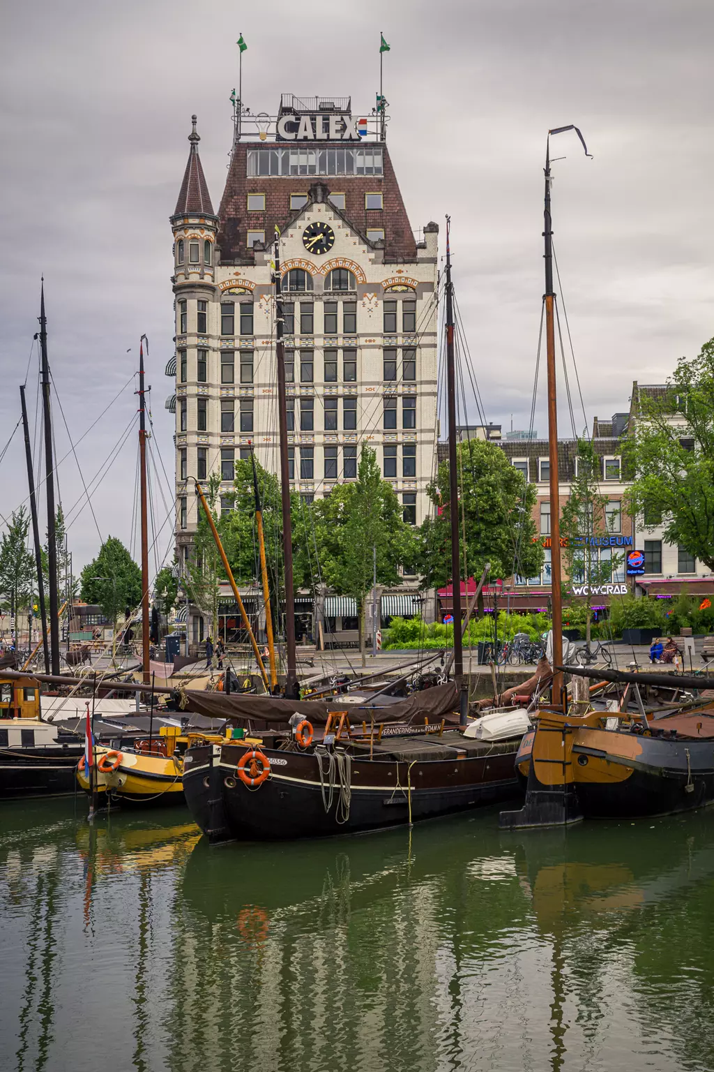 Black boats are moored in the water, with a historic building featuring a tower and clock in the background.