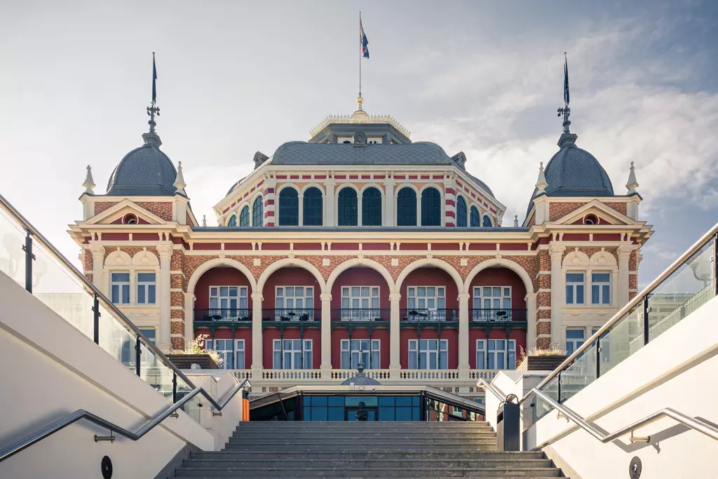 The historic building with colorful facades and large windows is surrounded by stairs leading to its entrance.