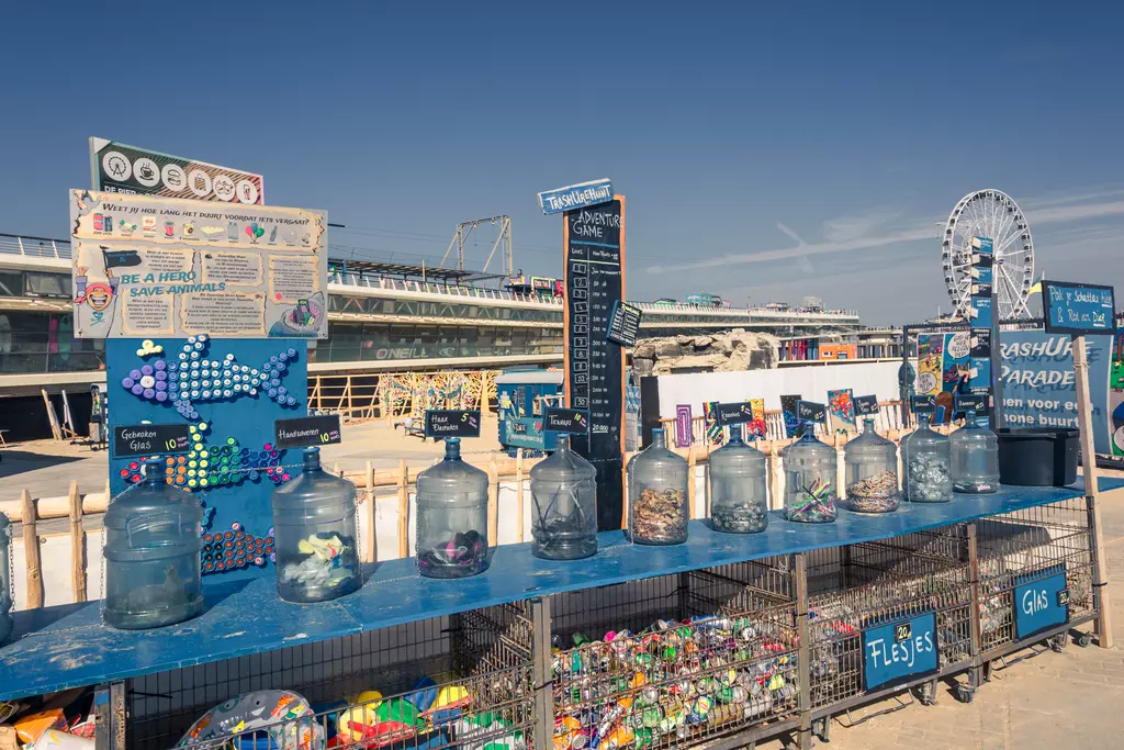 A stand with several glass containers holding various items, next to colorful toys and a Ferris wheel in the background.