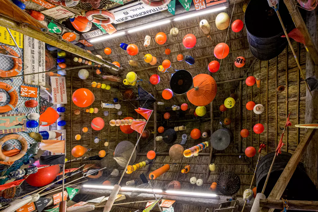 Bunte Bojen im Museum auf Texel: Viele farbige Schwimmkörper hängen von der Decke in einem einladenden Raum.