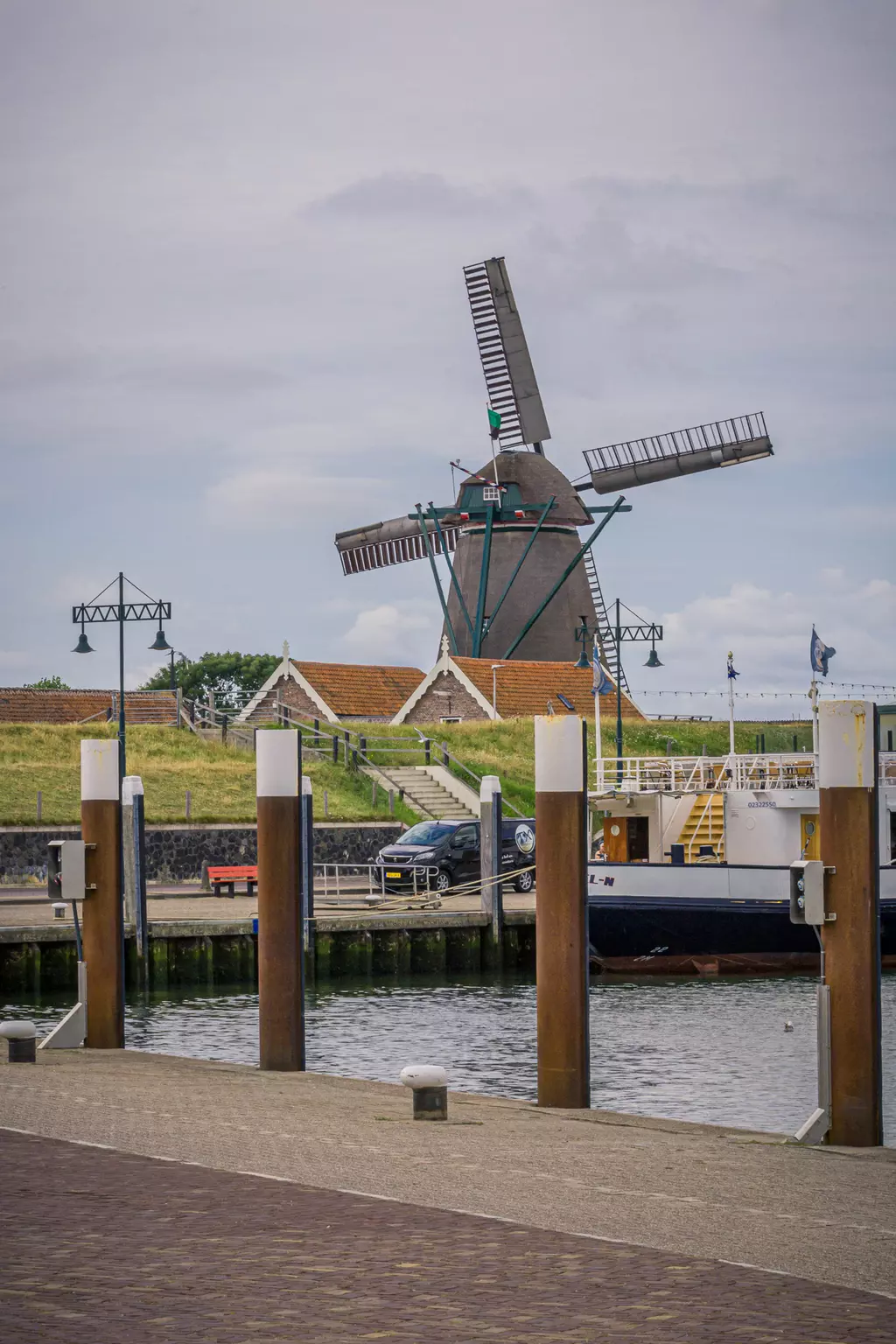 Windmühle auf Texel: Eine traditionelle Windmühle steht am Wasser, mit einem kleinen Hafen und Booten im Vordergrund.