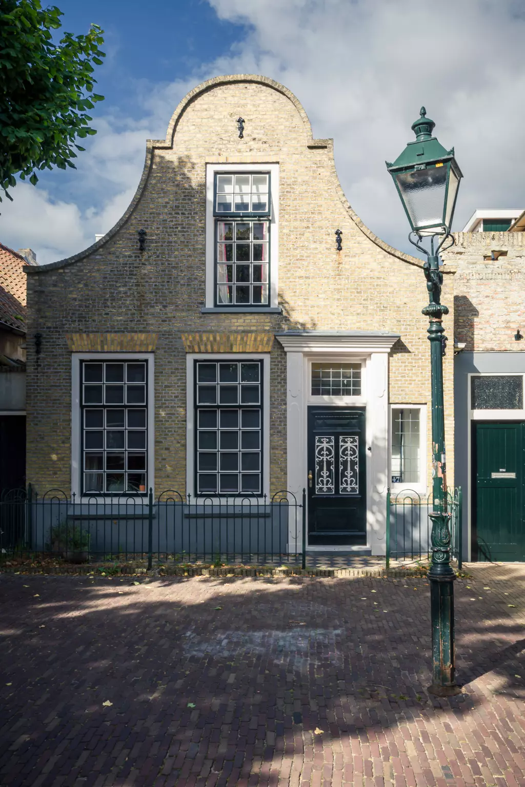 Haus in Terschelling: Ein historisches Gebäude mit Satteldach, großen Fenstern und einer gusseisernen Laterne davor.