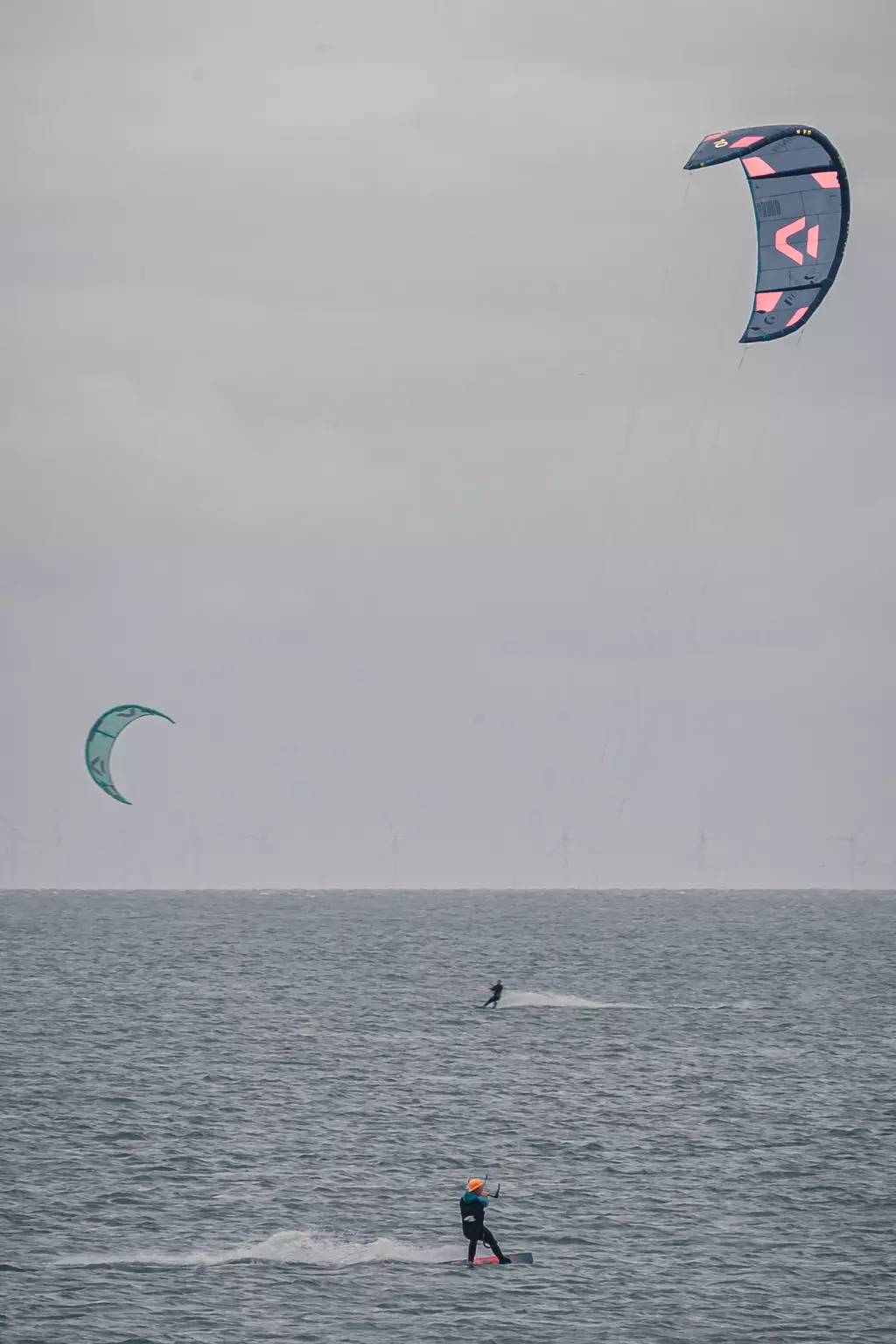 Kitesurfen auf Sylt: Ein Kitesurfer fährt über das Wasser, während zwei Kites über ihm in der Luft schweben.