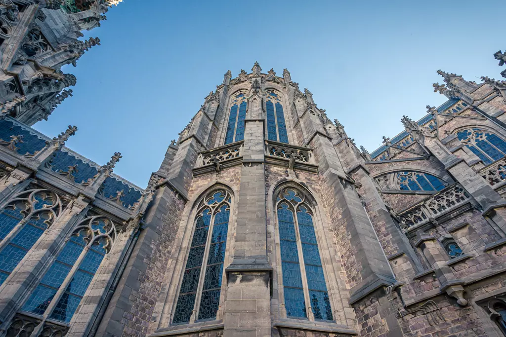 A detailed view of an impressive Gothic church featuring tall windows and ornate stonework under a blue sky.