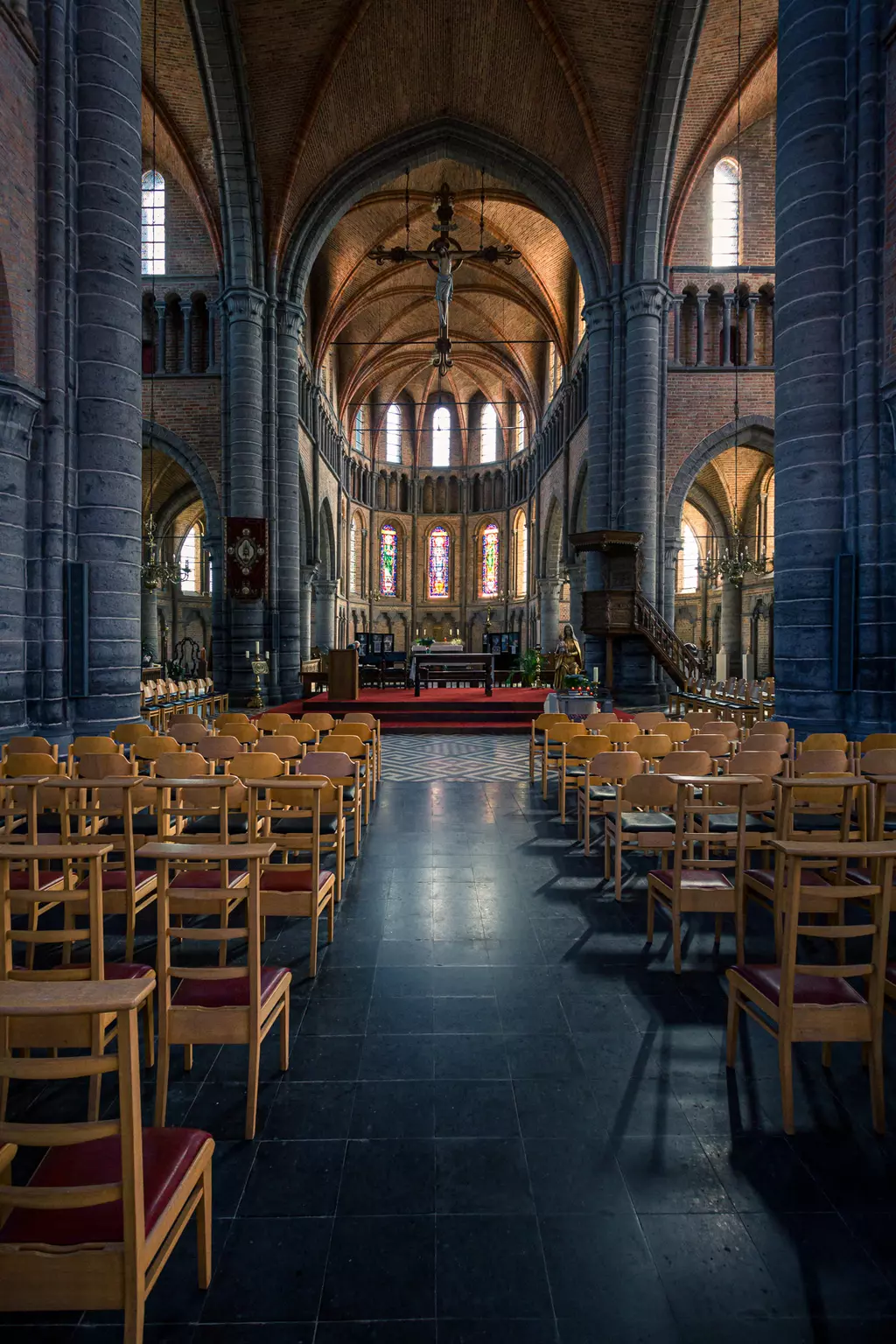 Helle Kirche mit hohen, gewölbten Decken, zahlreichen Holzbänken und bunten Fensterrahmen, die Licht ins Innere lassen.