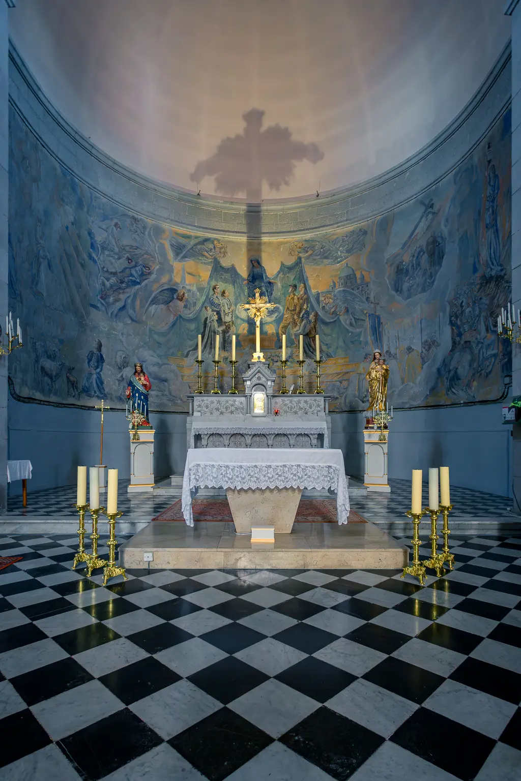 Kircheninnenseite in Cassis mit einem Fresko von Jean Lair, das Jeanne d'Arc und französische Soldaten darstellt. Im Vordergrund ein Altar mit Kerzen.