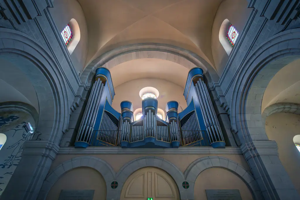Orgel in einer gewölbten Kirchenarchitektur in Cassis. Bunte Fenster ergänzen den sakralen Raum, der von sanftem Licht durchflutet wird.