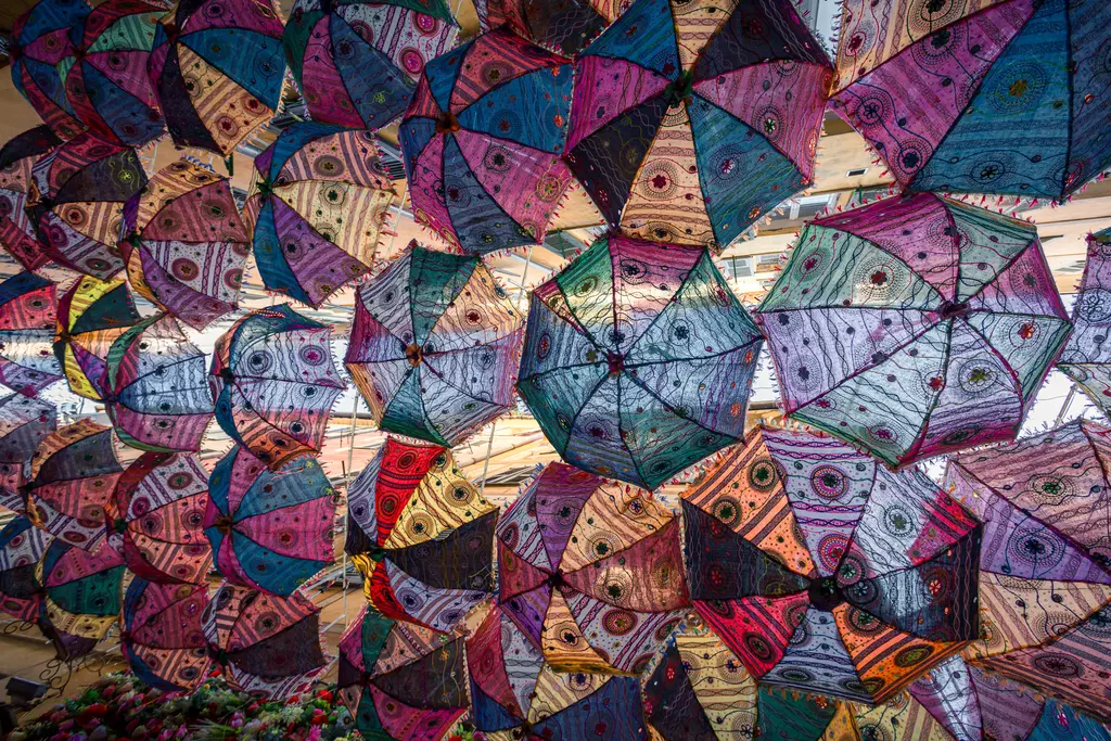 Colorful umbrellas hang decoratively from the ceiling, creating a vibrant, artistic atmosphere.