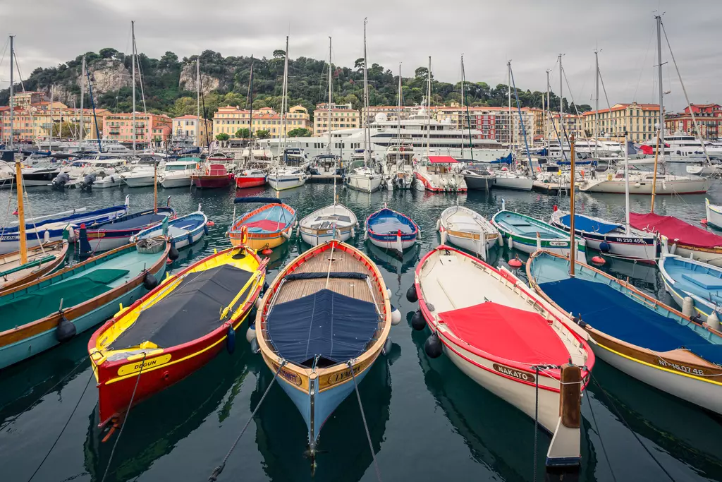 Boats in the Nice harbor: Colorful small boats rest peacefully in the water, surrounded by larger yachts and vibrant buildings in the background.