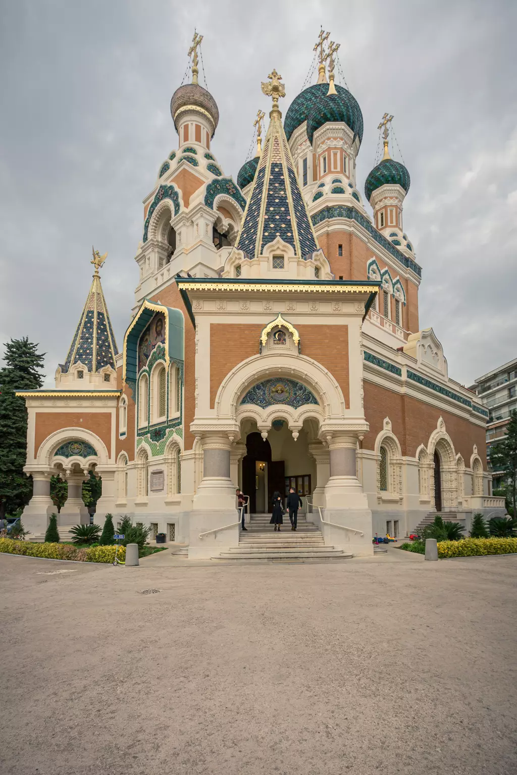 A colorful, architecturally ornate building featuring onion domes and golden topped spires. The sky is overcast.