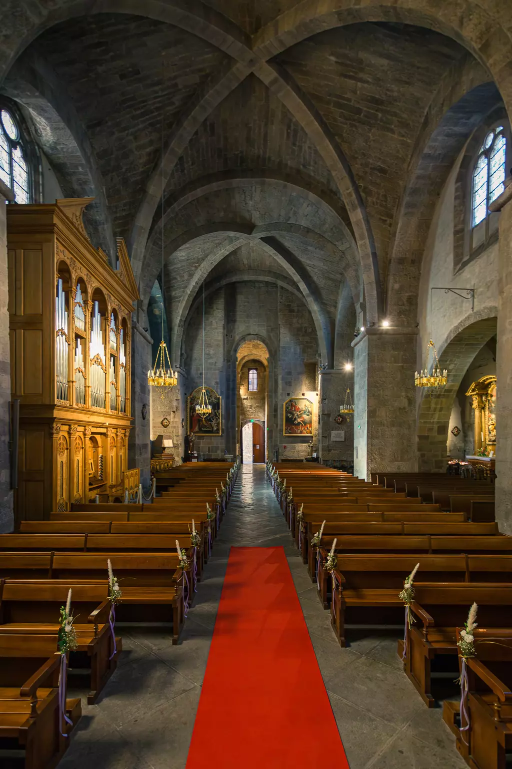 Eine lange Kirche mit einer roten Läufer, Holzbankreihen auf beiden Seiten und einem kunstvoll geschnitzten Altar im Hintergrund.