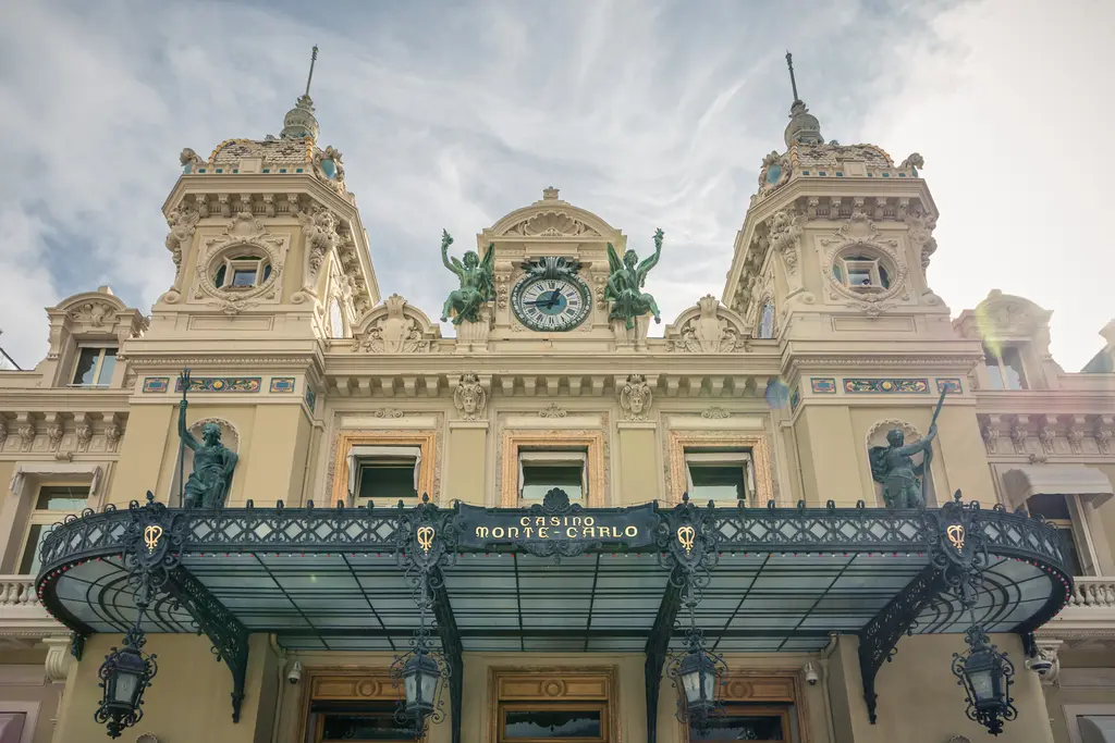 Monte Carlo Casino in Monaco: An ornate historic facade features intricate statues, decorations, and a large clock tower.