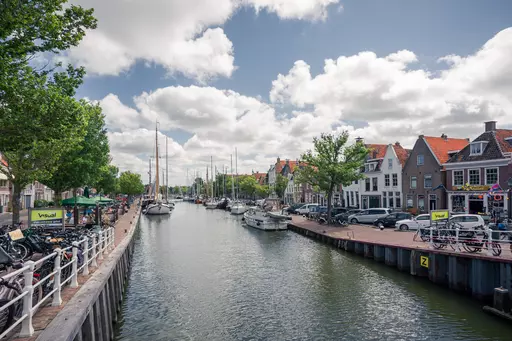 Canal in Harlingen: A serene canal lined with sailboats and historic buildings under a cloudy sky.