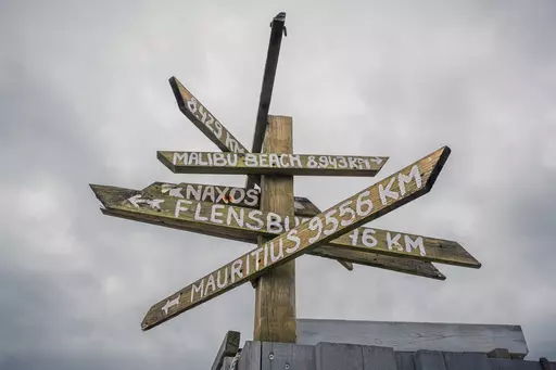 Wegschild auf Sylt: Holzschild mit Entfernungsangaben zu verschiedenen Orten, darunter Malibu Beach, Flensburg und Mauritius.