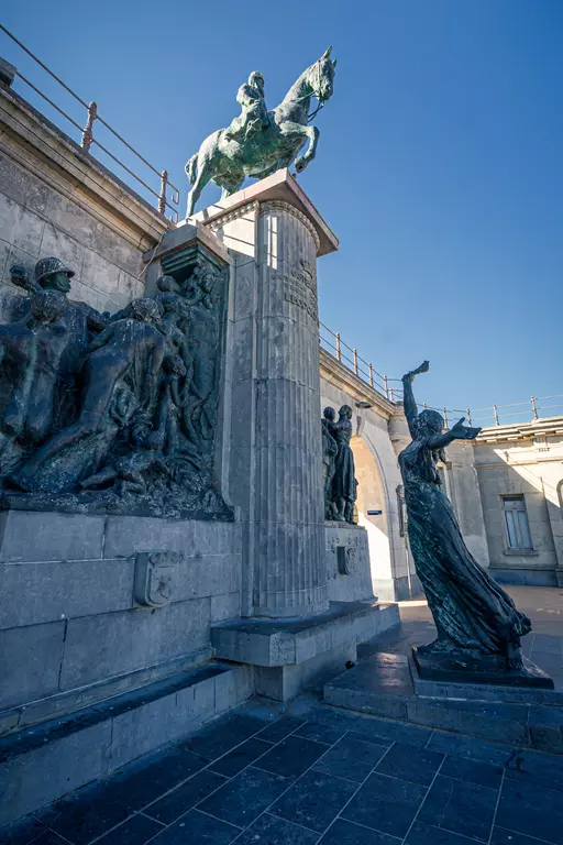 A monumental statue of a rider on a tall pedestal, surrounded by additional sculptures and an architectural wall.