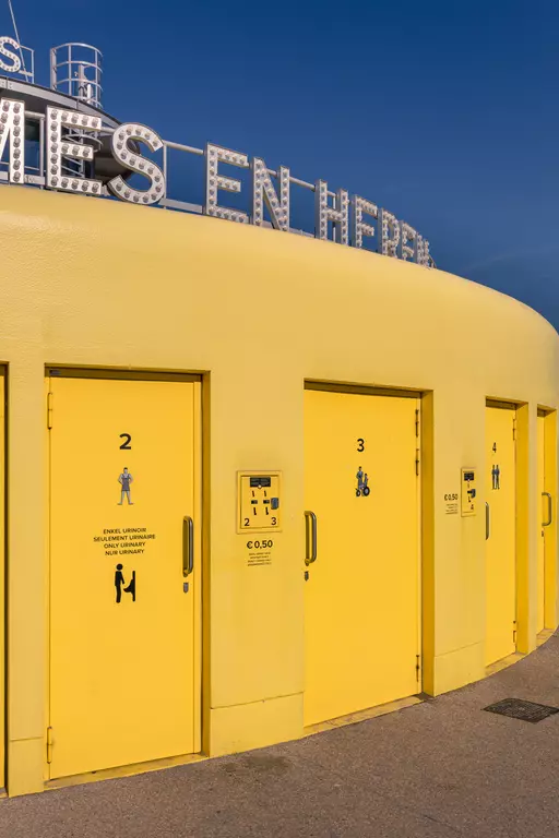 Yellow changing cabins with numbers on a round structure, featuring usage information and fees underneath.