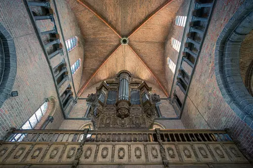 Eine Innenaufnahme einer Kirche mit hoher Decke, sichtbarem Holzbalustrade und großer Orgel im Hintergrund.