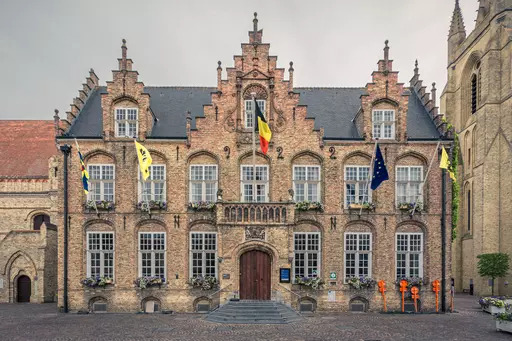 The building features a gothic-style façade with ornate windows and flags, surrounded by inviting flower arrangements.