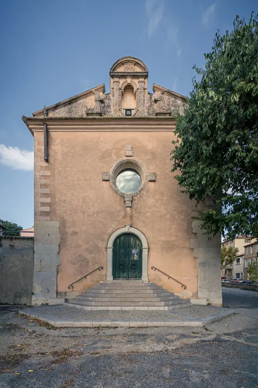 Chapelle des Pénitents Bleus in La Ciotat, featuring a pink facade, round window, and steps leading to a green door.