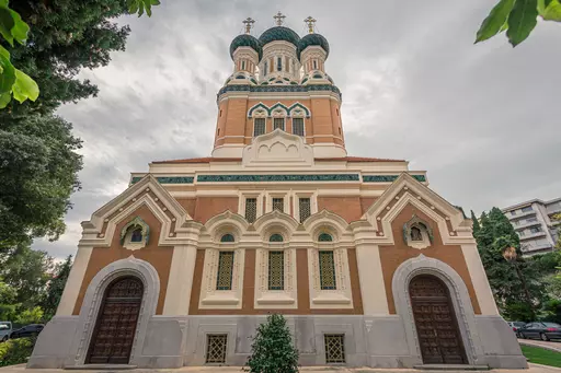 A colorful building with an impressive facade topped by three copper domes.