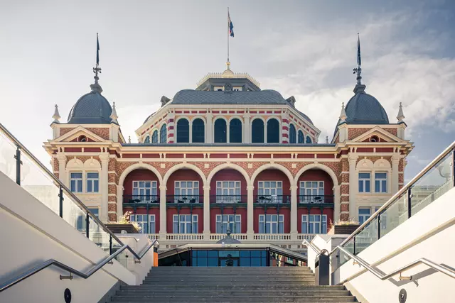 Das historische Gebäude mit bunten Fassaden und großen Fenstern ist von einer Treppe umgeben, die zu seinem Eingang führt.