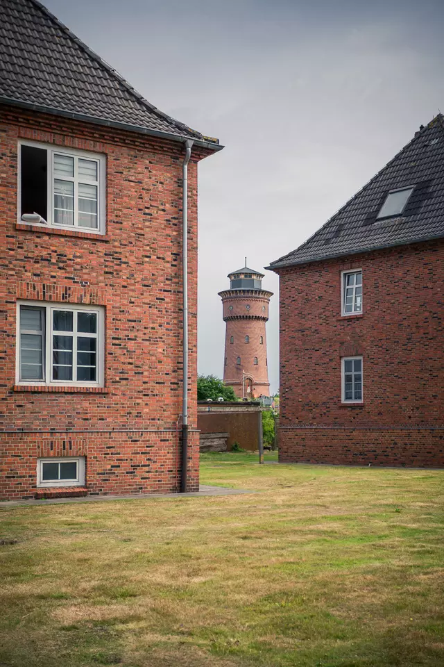 Blick durch eine Wohnsiedlung auf den Wasserturm von Borkum.