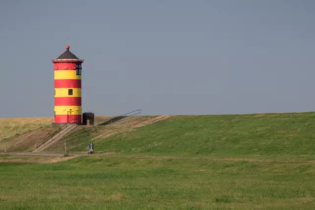 Der Pilsumer Leuchtturm steht farbenfroh in der Nähe von Greetsiel auf dem grünen Deich.