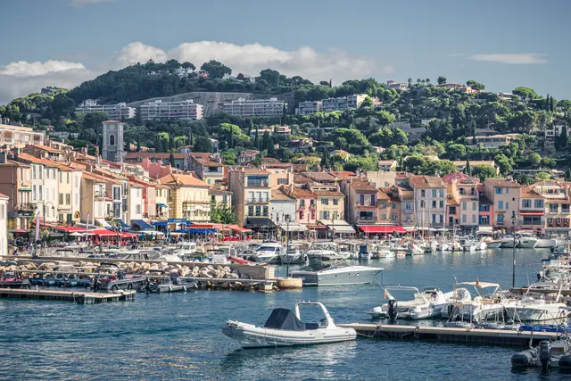 A picturesque view of Cassis harbor, featuring colorful waterfront buildings and numerous boats docked in the calm water.